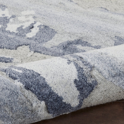 Soft plush shag rug in blue-gray tones with abstract ivory patterns, ideal for living room decor.