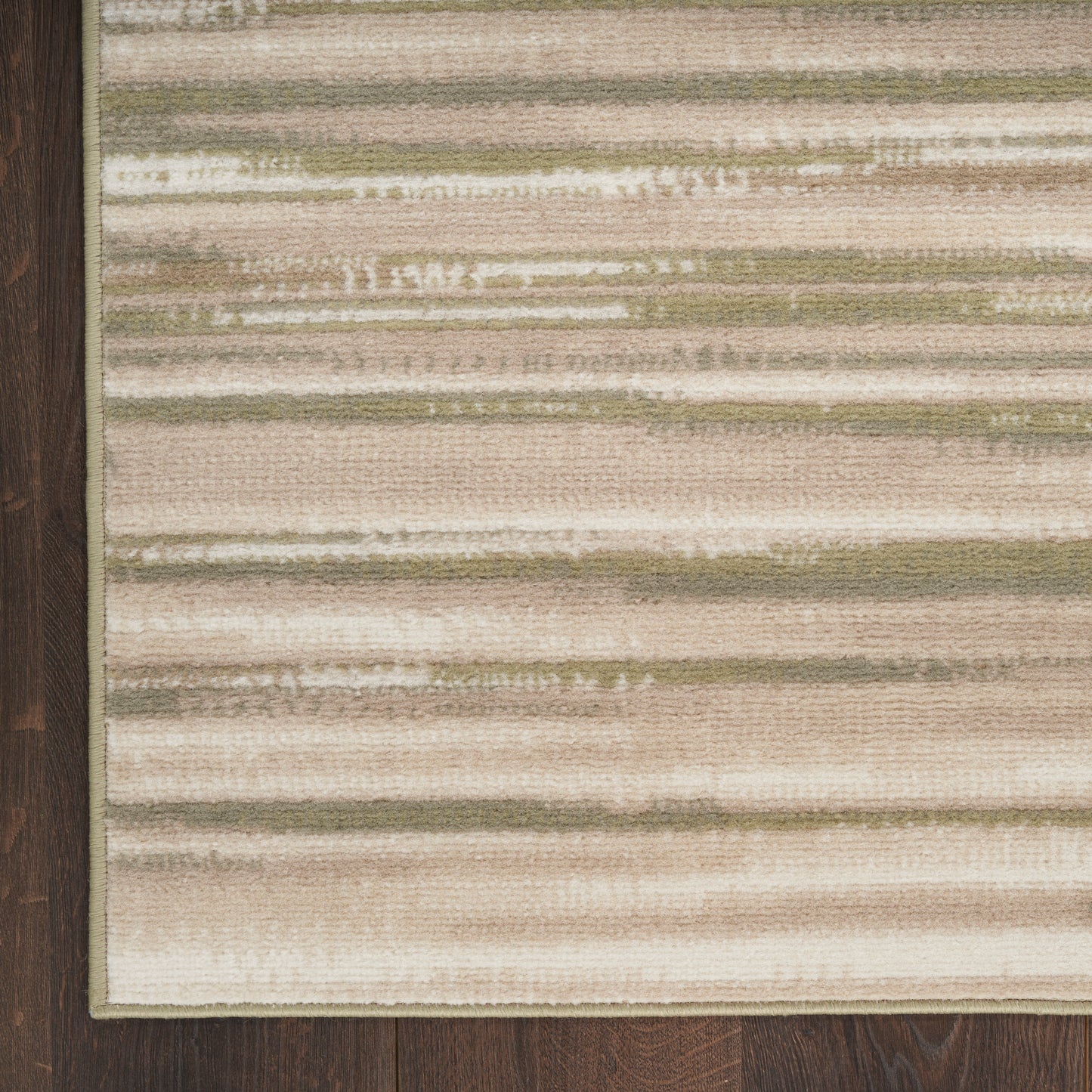Beige striped area rug with cream, taupe, and sage horizontal bands on dark wood floor.