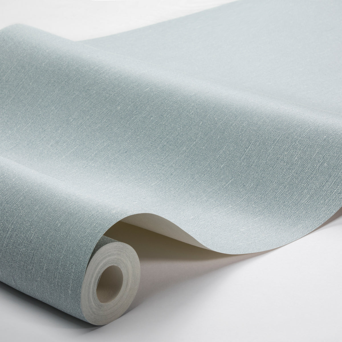 Light blue linen-textured wallpaper roll with subtle fabric grain; curled edge exposes inner core.