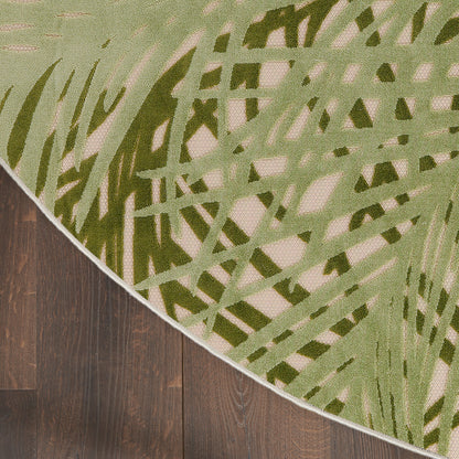 Modern area rug with olive-green abstract blade pattern on beige base, curved edge over dark wood floor.