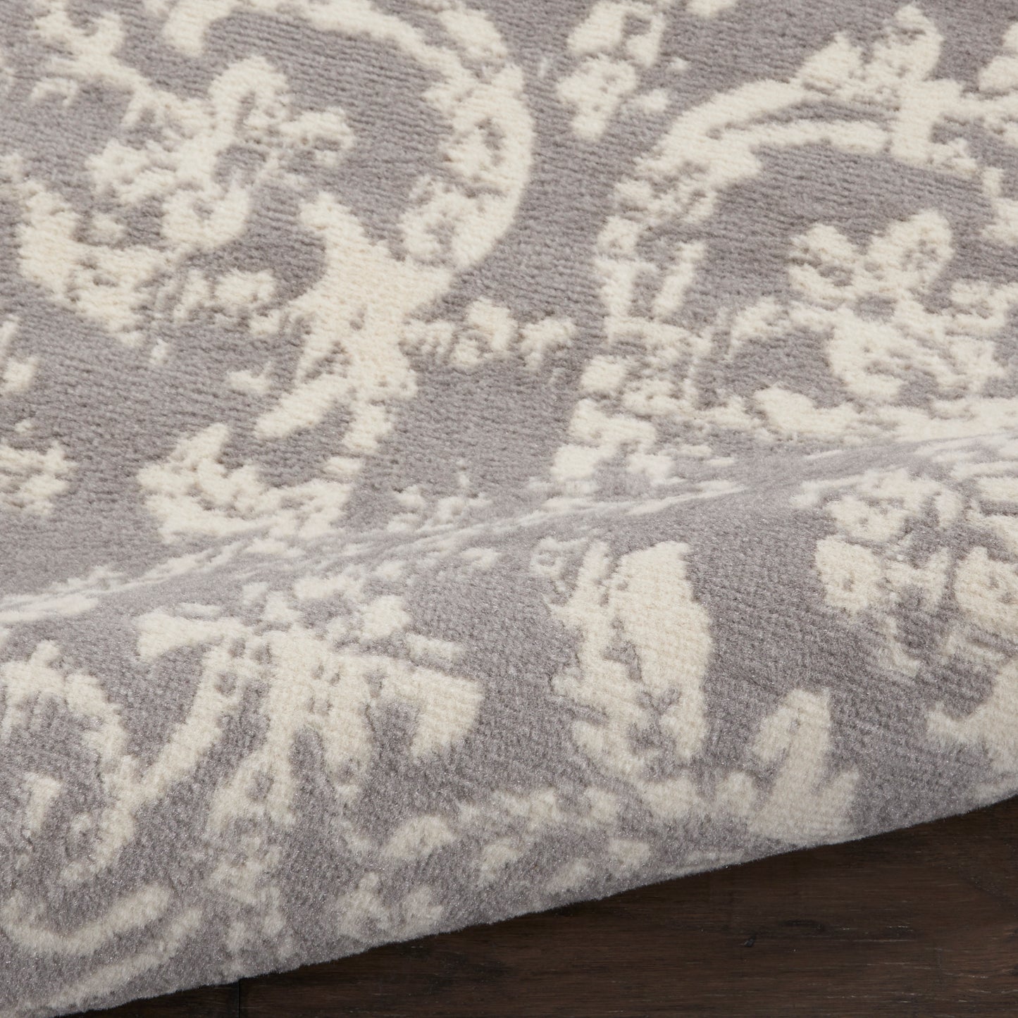 Taupe rug with white damask floral pattern, plush textured weave, ideal for living room or bedroom.