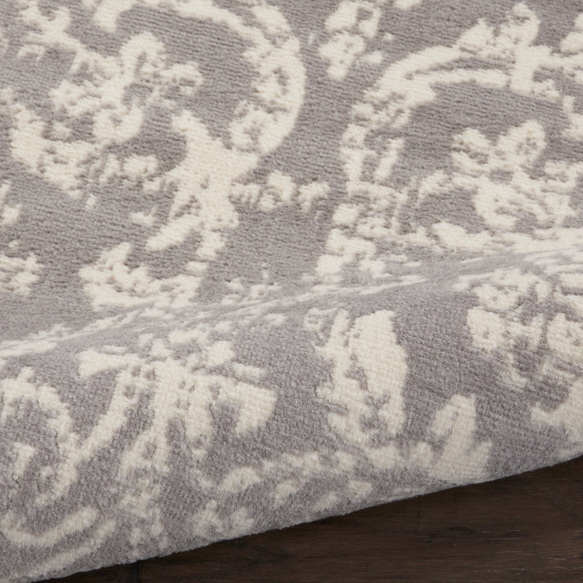 Taupe rug with white damask floral pattern, plush textured weave, ideal for living room or bedroom.