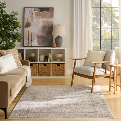 Neutral living room with beige sofa, wooden armchair, gray patterned rug, white cubby shelving with wicker baskets.