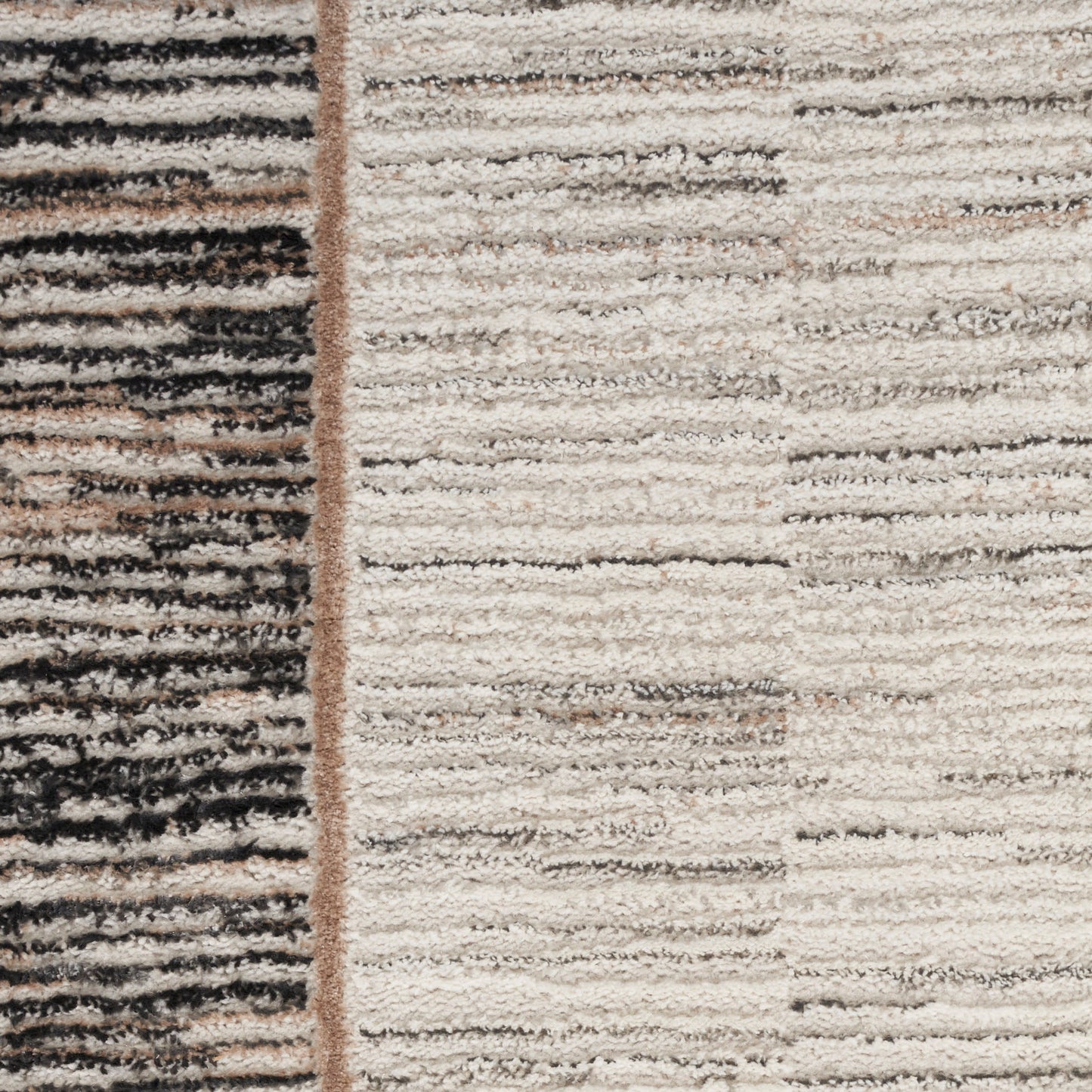 Close-up of a textured beige rug with cream and black striped panels separated by a brown seam.