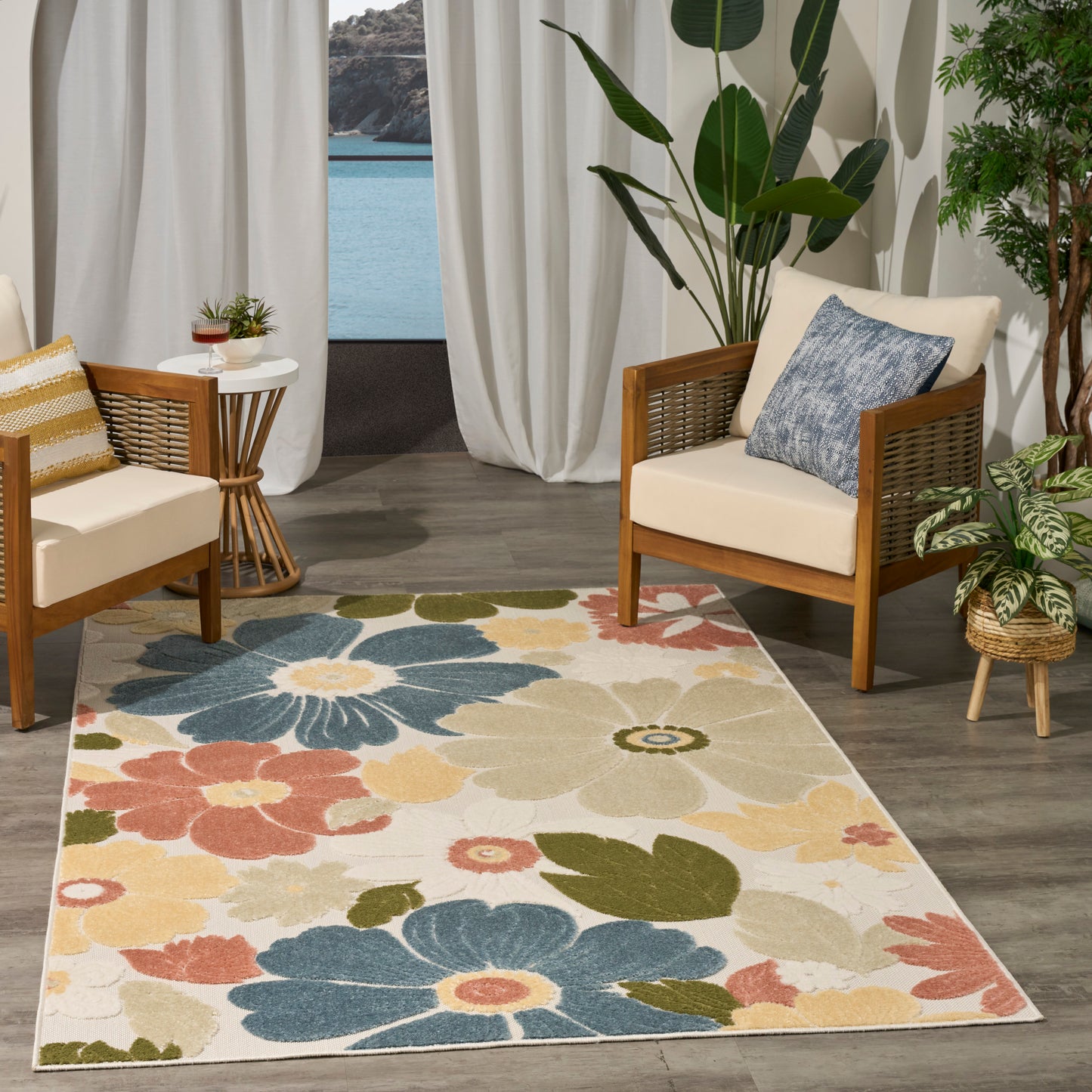 Colorful floral rug with blue, yellow, pink and green blooms; wooden lounge chairs with beige cushions in a tropical room.