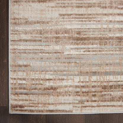 Rectangular beige and light blue distressed area rug on dark wood floor; abstract brushstroke pattern.
