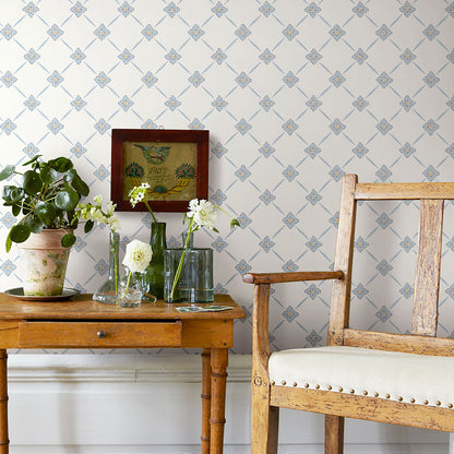 Rustic wooden side table with plant, glass vases of white flowers, framed art, beside a weathered upholstered armchair.