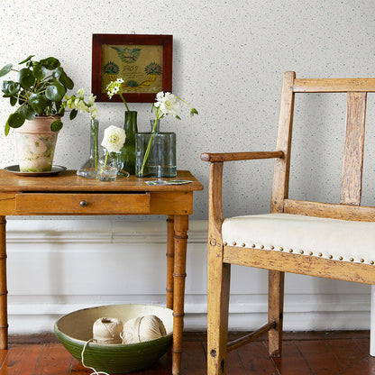 Rustic wooden side table with glass vases and white flowers, vintage chair beside, potted plant and twine bowl.
