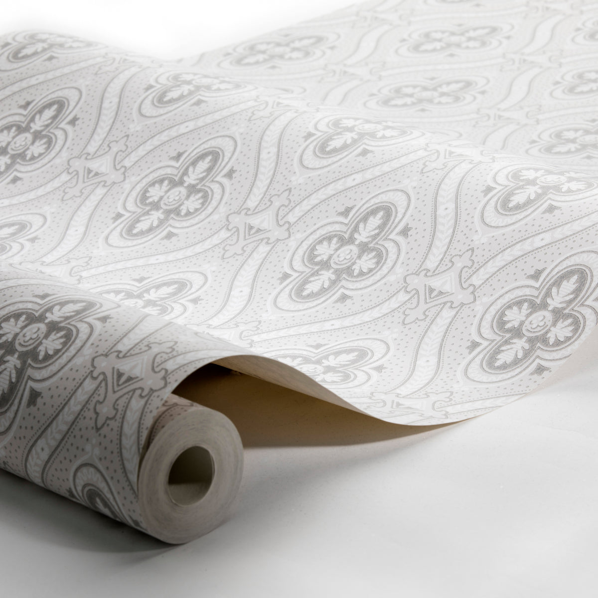 Rolled wallpaper with light gray floral damask pattern on white, unfurling to show intricate repeating design.