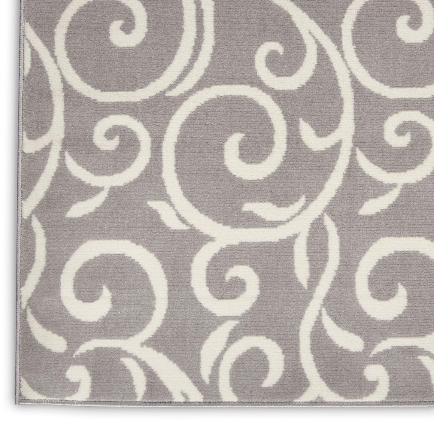 Grey area rug with white swirling scroll pattern, soft textured surface, light border along the edges.