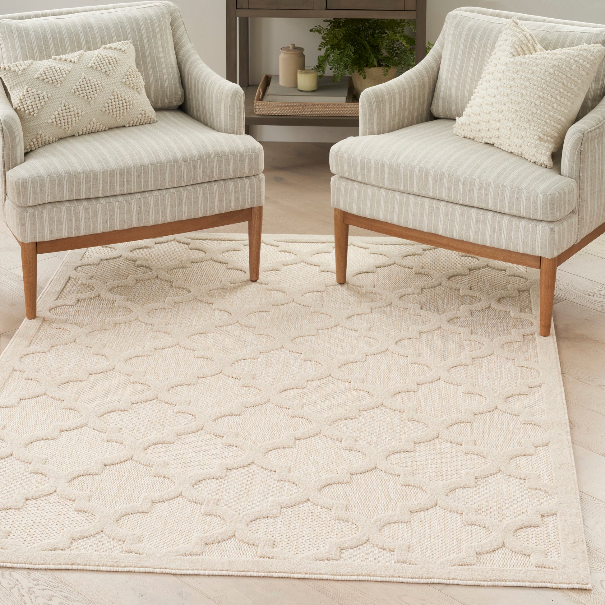 Cream striped armchairs with light wood legs on a beige lattice rug in a neutral living room.