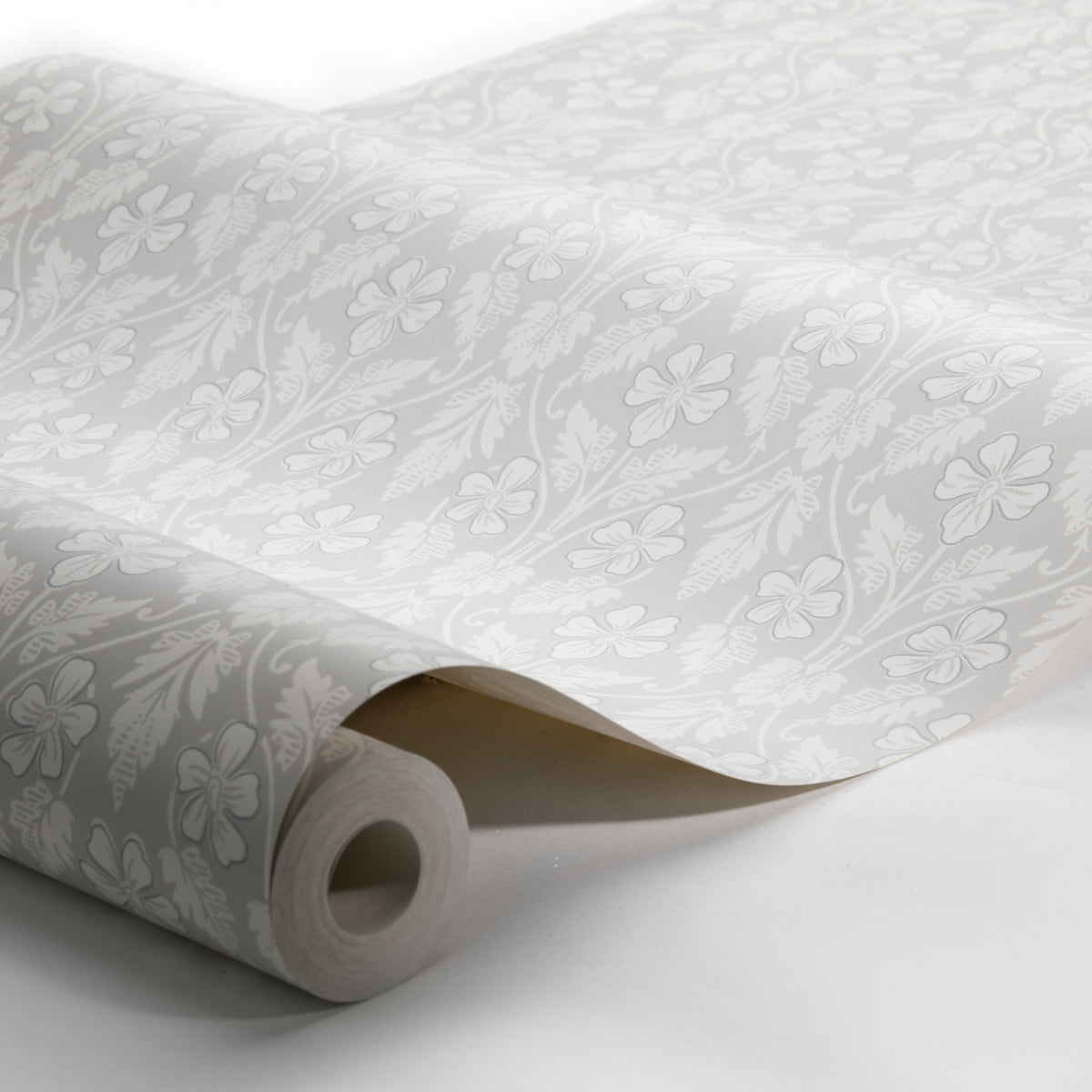 Roll of light gray wallpaper with white floral damask pattern and curled edge.