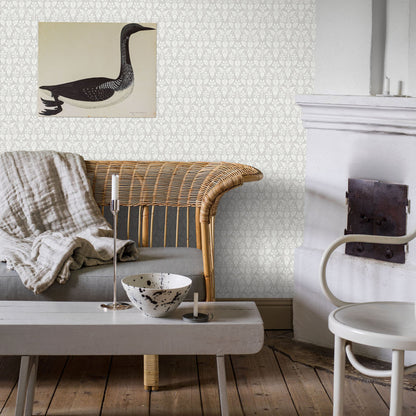 Living room with gray damask wallpaper, wicker sofa, linen throw, white coffee table, speckled bowl, candle, duck wall art.