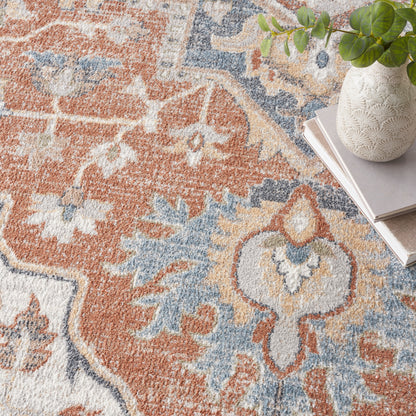 Oriental-style rug in rust, blue & cream with floral motifs; white textured vase with green plant atop stacked magazines.