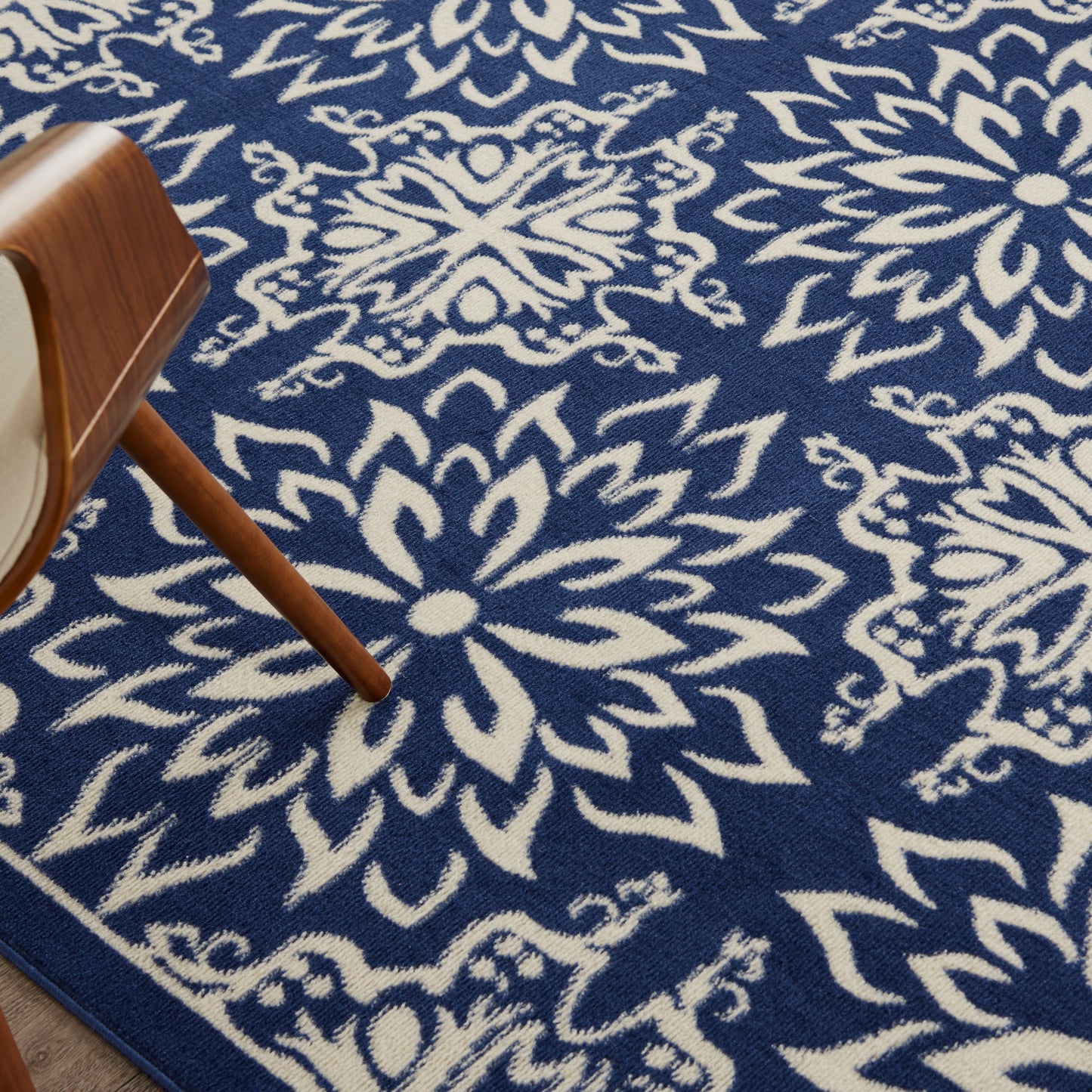Blue rug with white floral medallion pattern; wooden chair leg visible on the left.