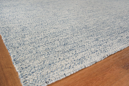 Light blue textured rug with a dense loop pile on a warm wood floor.
