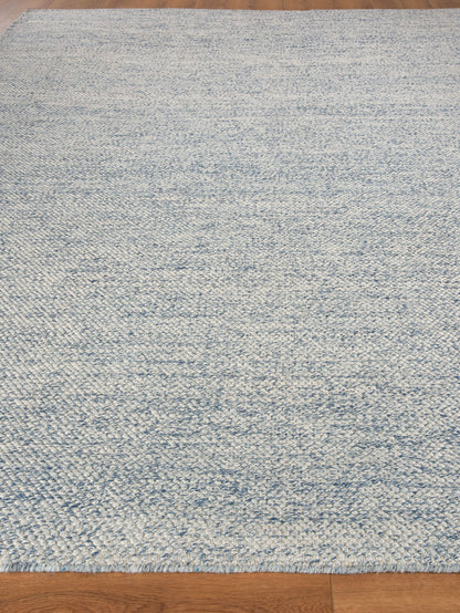 Rectangular blue and ivory marled hand loomed rug on hardwood floor.