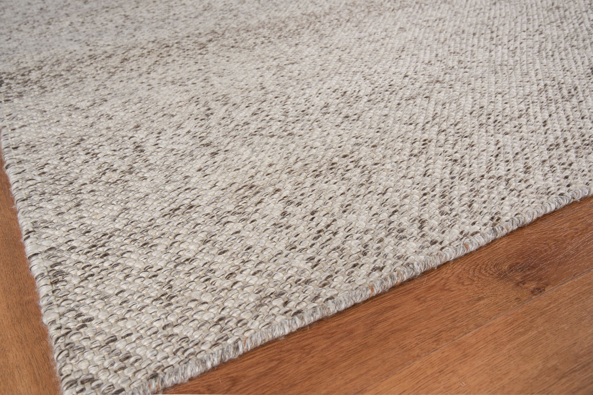 Gray-beige hand-loomed rug with speckled texture on warm wood floor; rectangular 8' x 10' rug for casual contemporary decor.