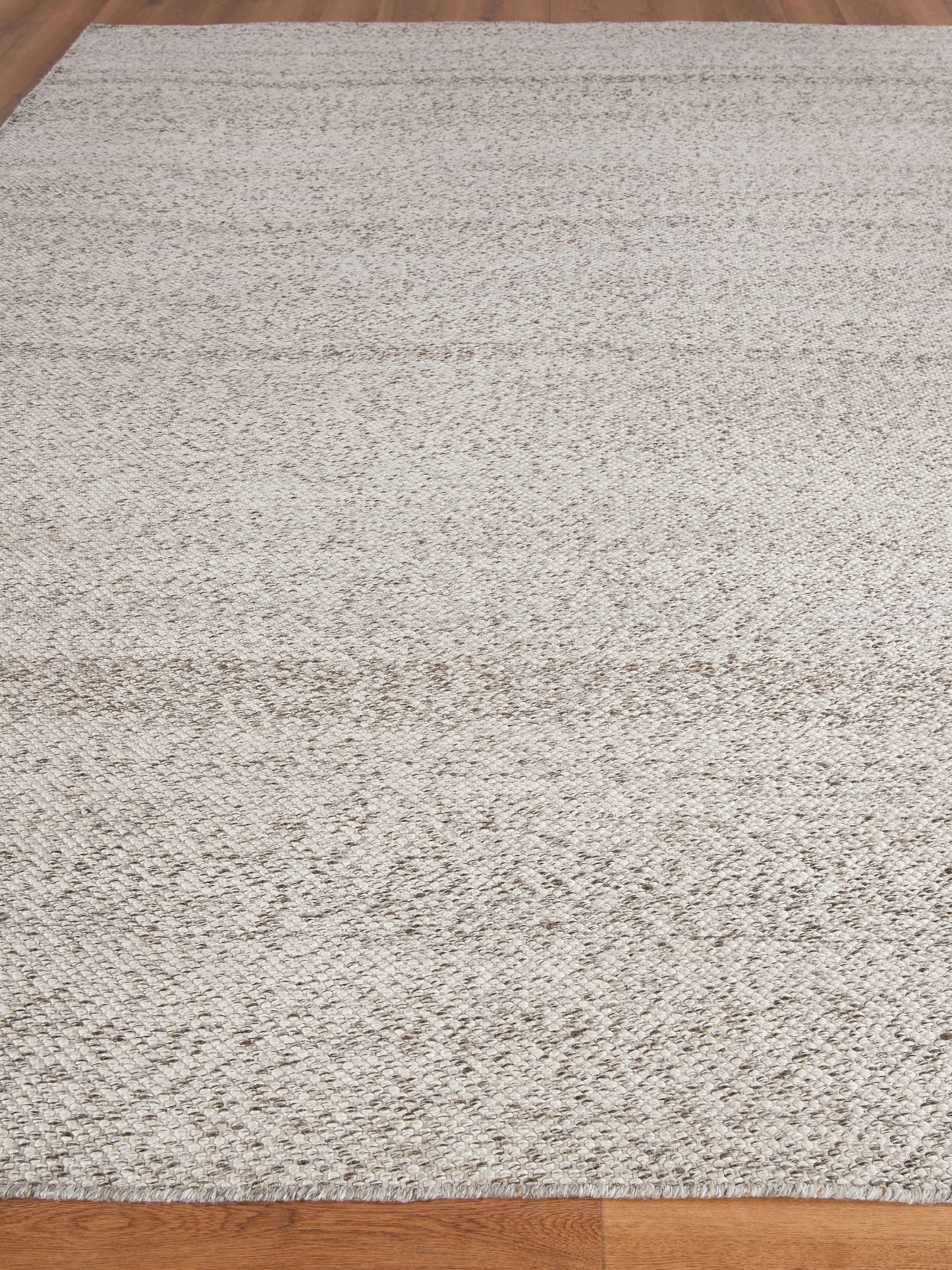 Rectangular cream beige textured area rug with a soft shag-like pile on a wooden floor.