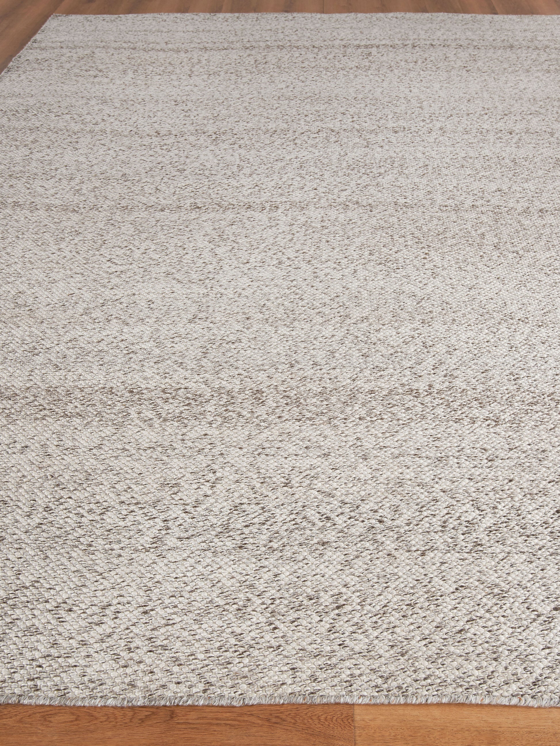 Rectangular cream beige textured area rug with a soft shag-like pile on a wooden floor.