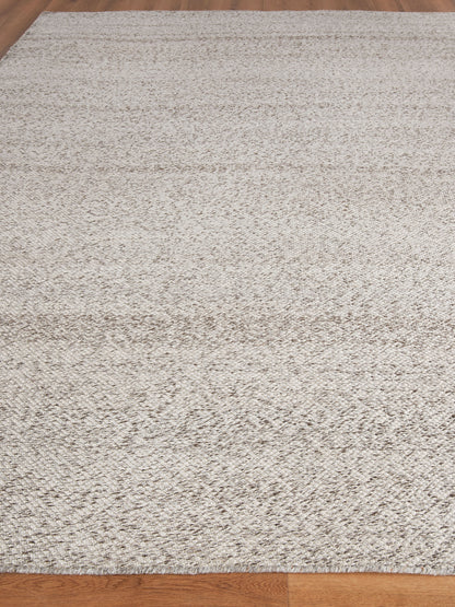 Rectangular cream beige textured area rug with a soft shag-like pile on a wooden floor.