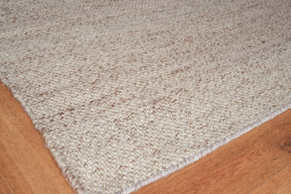 Beige textured loop-pile area rug on warm wood floor; rectangular, cozy casual style for living room or entryway.
