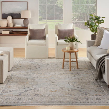 Neutral living room with cream armchairs, brown pillows, beige sofa, round wood side table with plant and candle, gray rug.