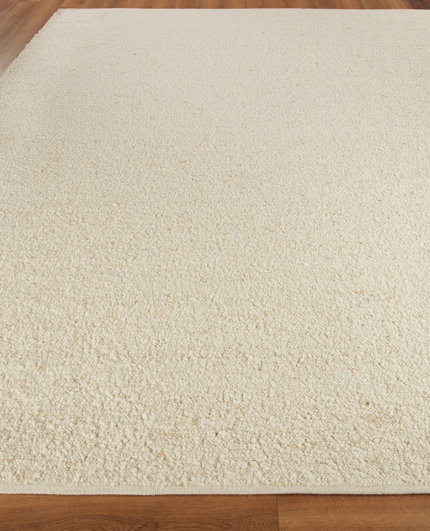 Cream textured rug with flat weave on hardwood floor, rectangular indoor decor.
