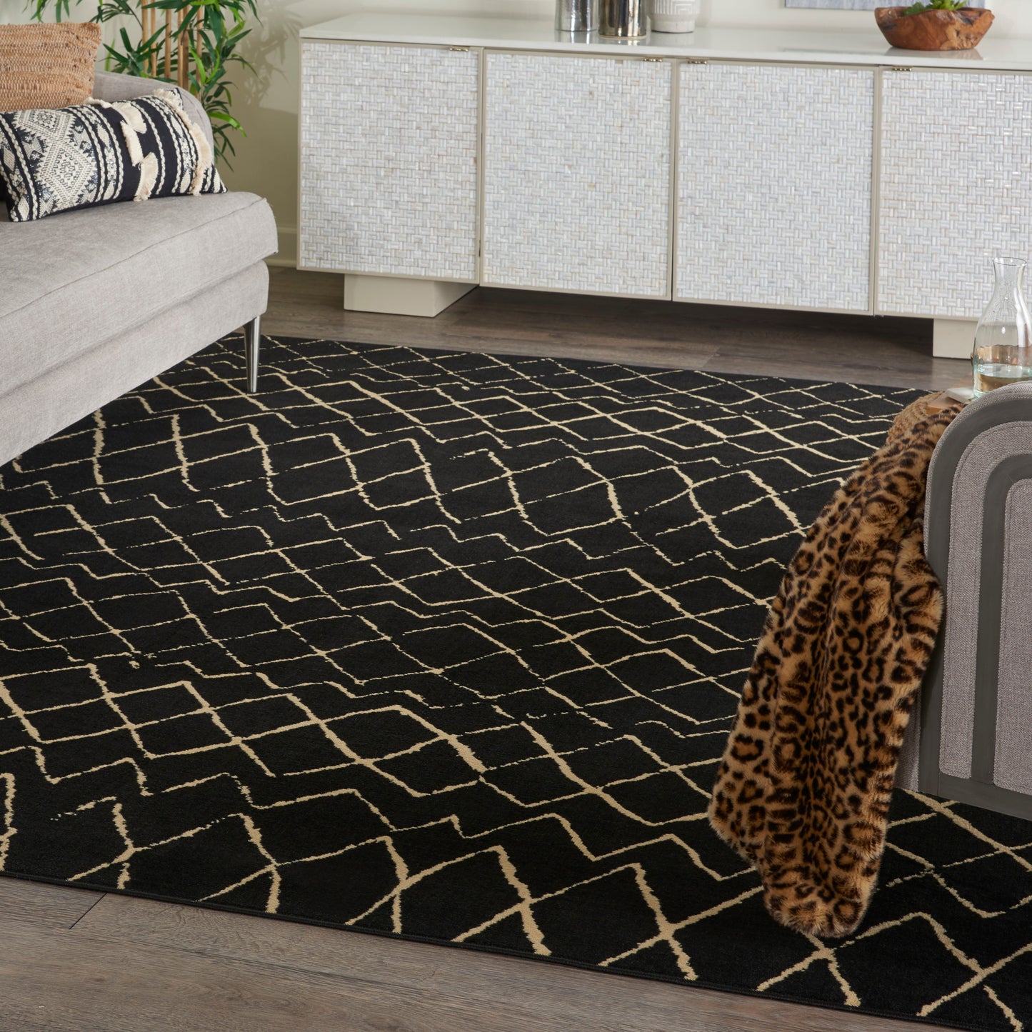 Black area rug with cream geometric lattice pattern in a modern living room with light sofa and leopard throw.