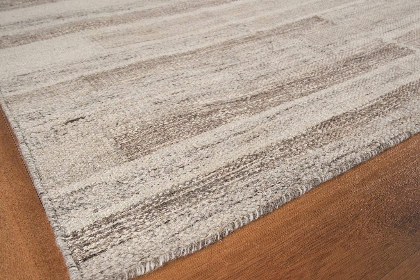 Rectangular beige and ivory woven area rug with subtle taupe stripes and bound edge on wood floor.