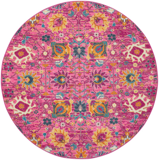 Pink round rug with vibrant floral and geometric pattern in yellow, teal, and orange; boho oriental style.