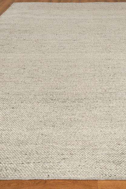 Light beige woven area rug with subtle texture on hardwood floor.