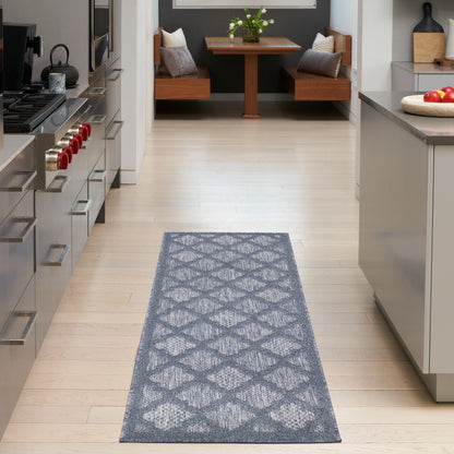 Gray geometric-patterned rug runner on light wood floor in modern kitchen with stainless steel appliances.
