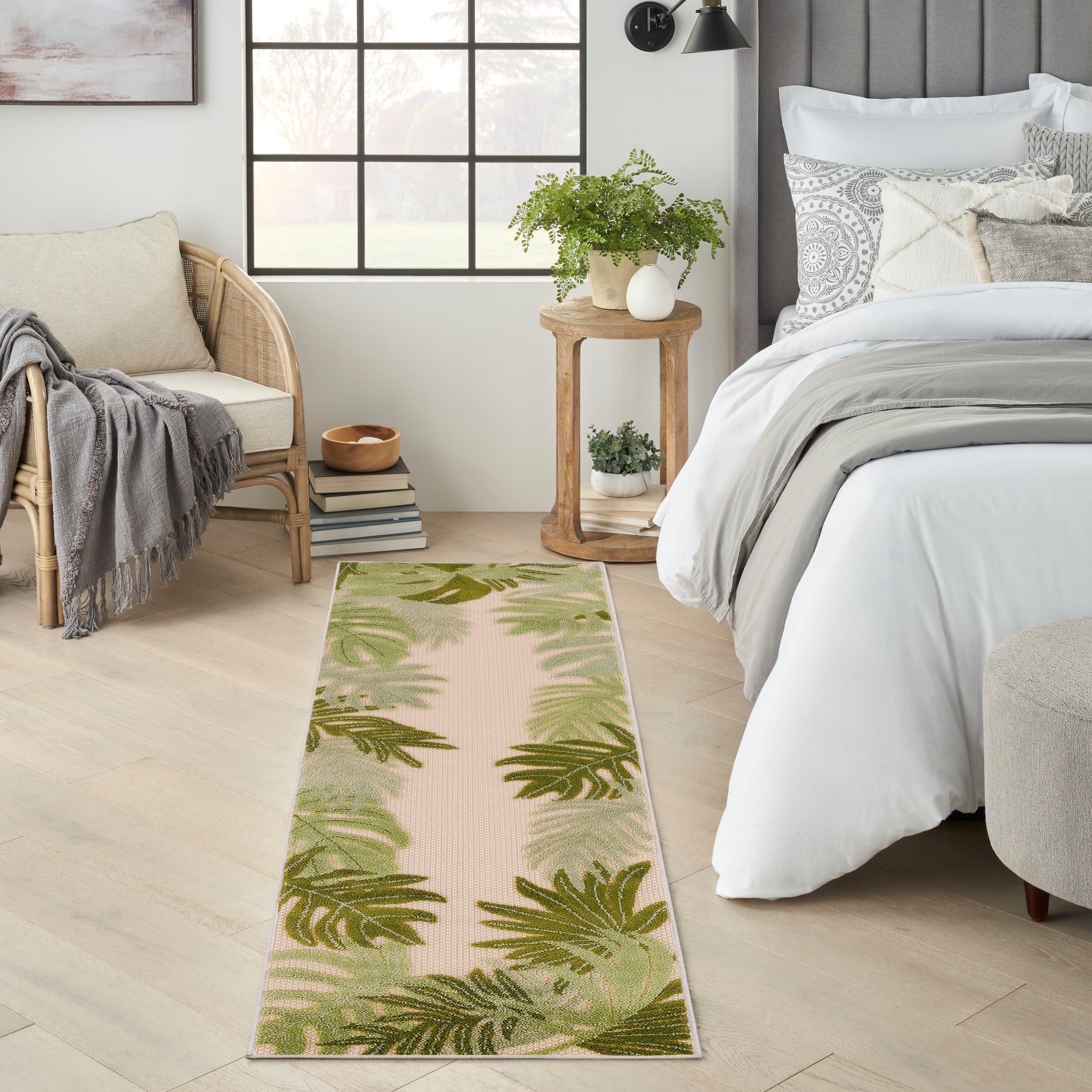 Long woven runner rug with green palm leaf pattern on pale pink-beige, adds natural calm to a serene bedroom.