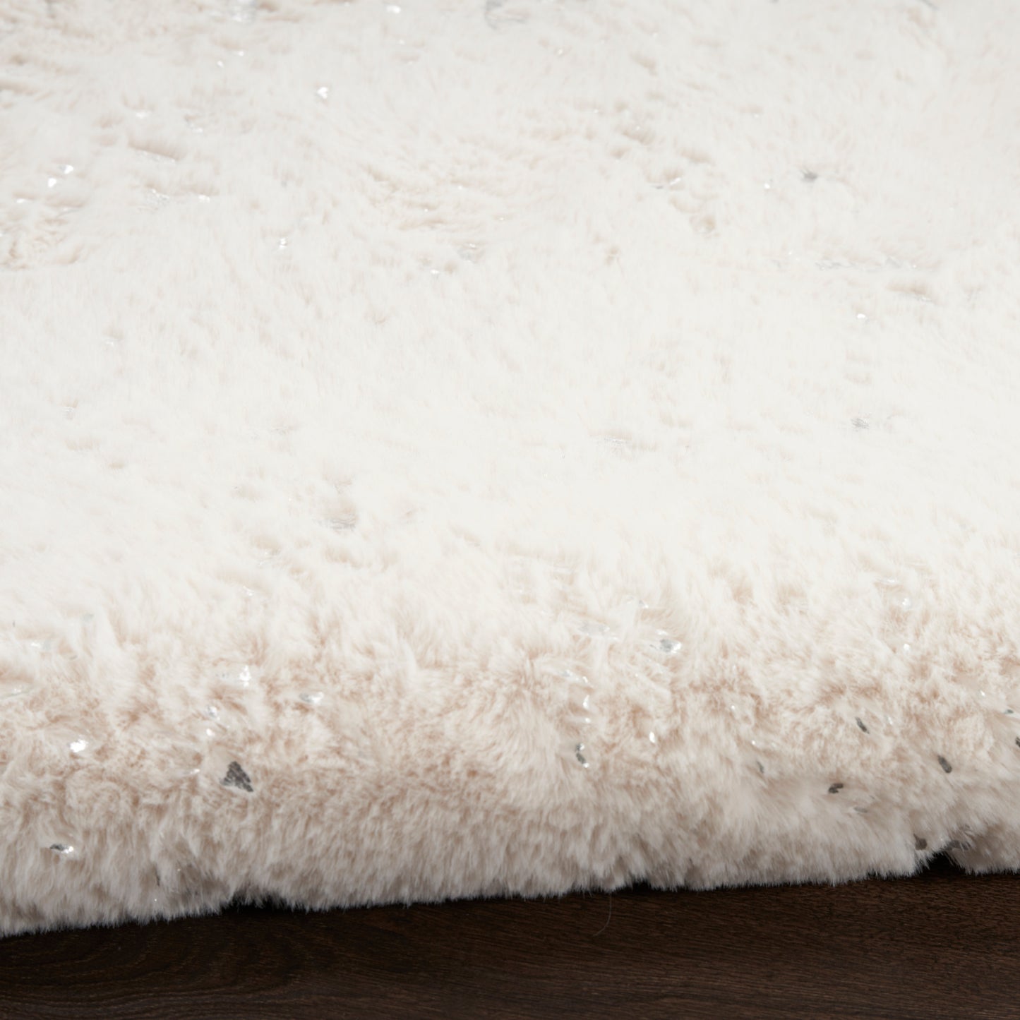 Soft white plush shag rug with dense pile on dark wooden floor.