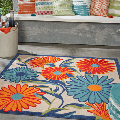 Colorful floral area rug with oversized orange and teal daisies, beige background and blue border.