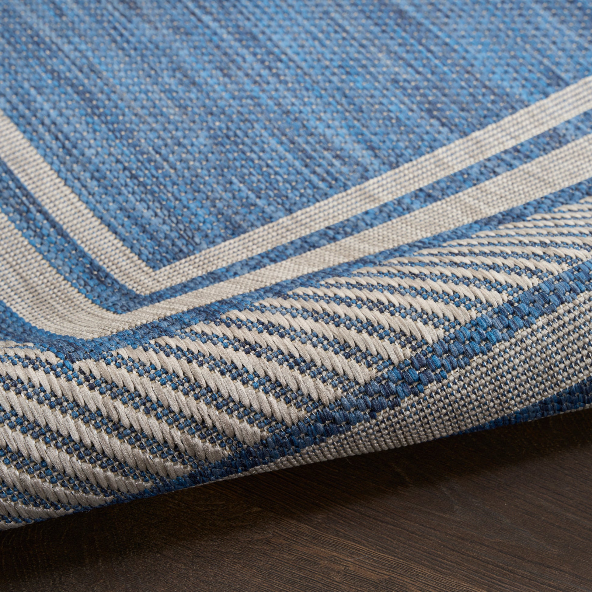 Blue denim-style woven rug with cream border and striped edge, casual floor mat.