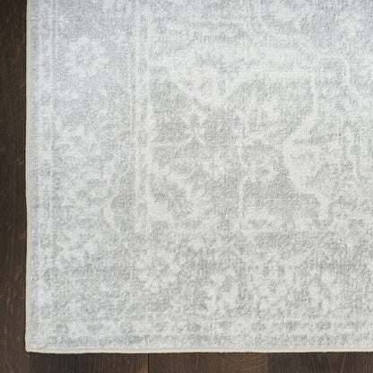 Rectangular light gray patterned area rug with a soft plush pile on dark wood floor.