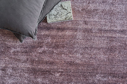 Dusty purple textured area rug with a dark gray pillow resting on its corner; plush, soft pile for contemporary living spaces.