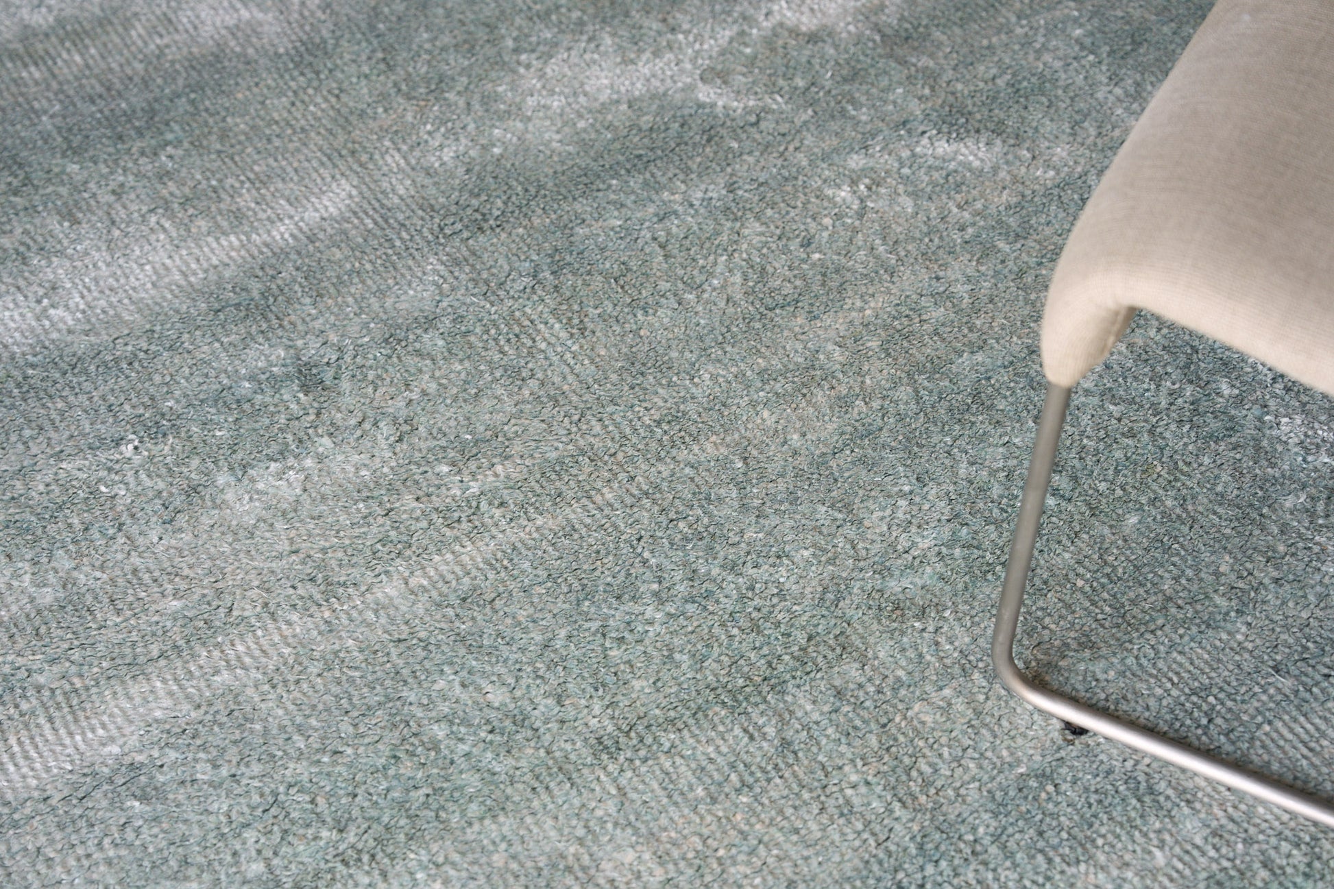 Partial view of a beige plush indoor hand-knotted rug with a textured surface.