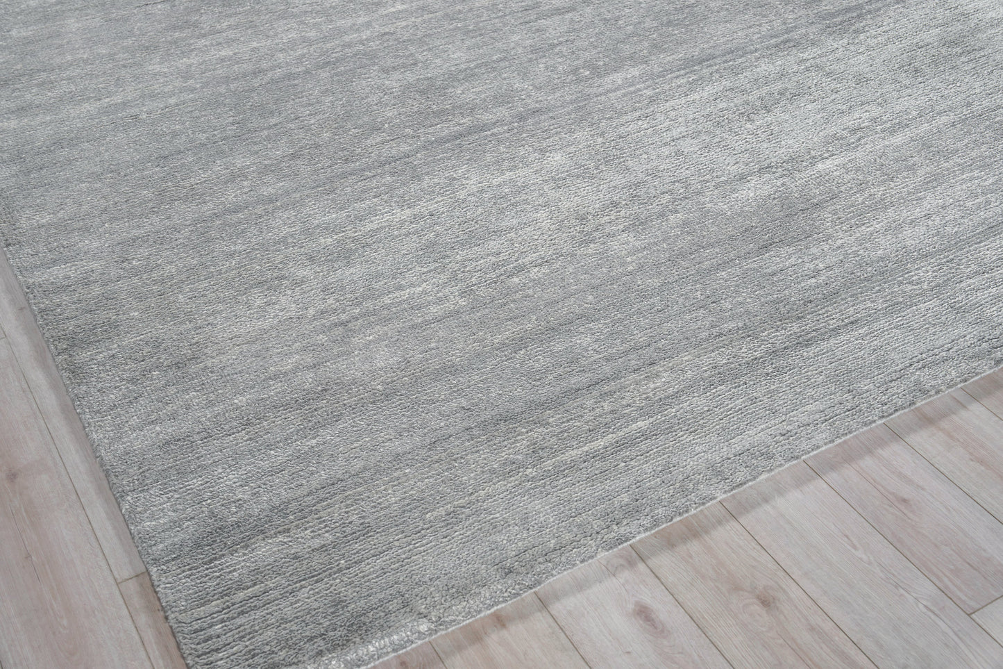 Rectangular gray textured rug with subtle heathered tones on light wood floor.