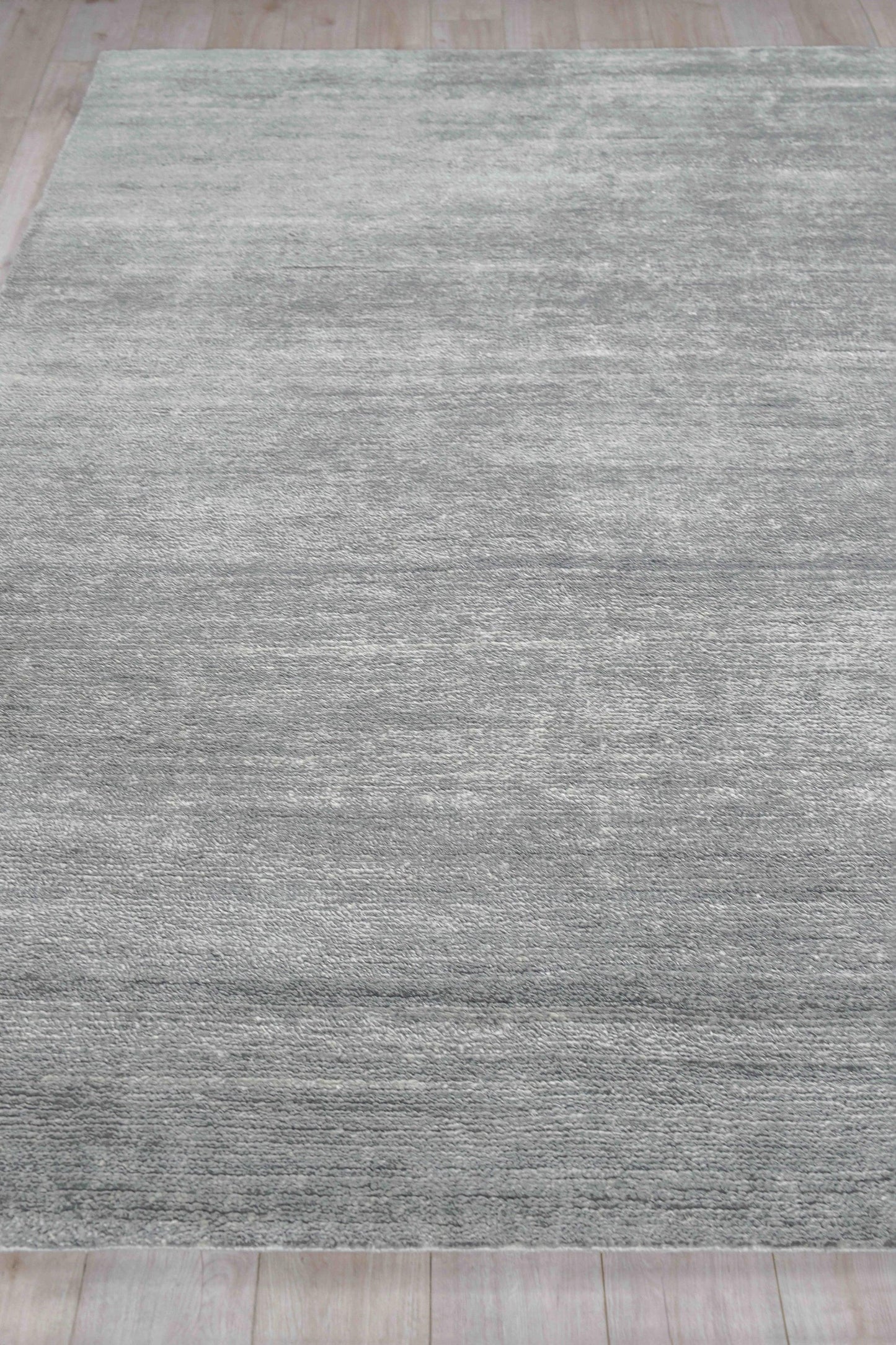 Gray textured hand-knotted indoor area rug with tonal variation on a light wood floor, 2' x 3'.