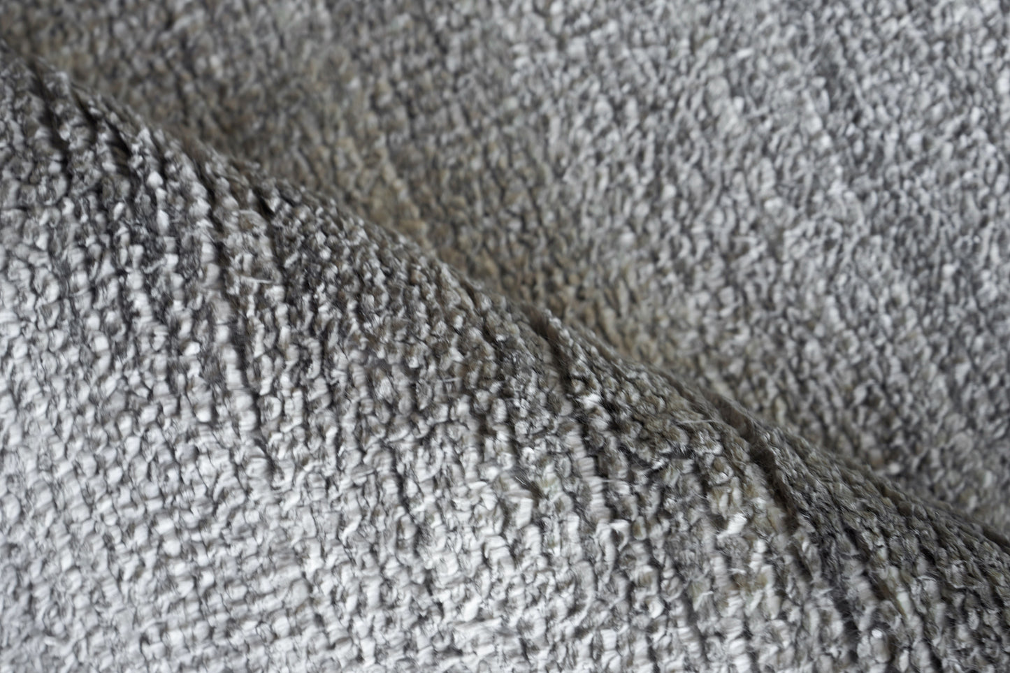 Close-up of plush gray rug fibers with a looped texture; indoor hand-knotted rug.