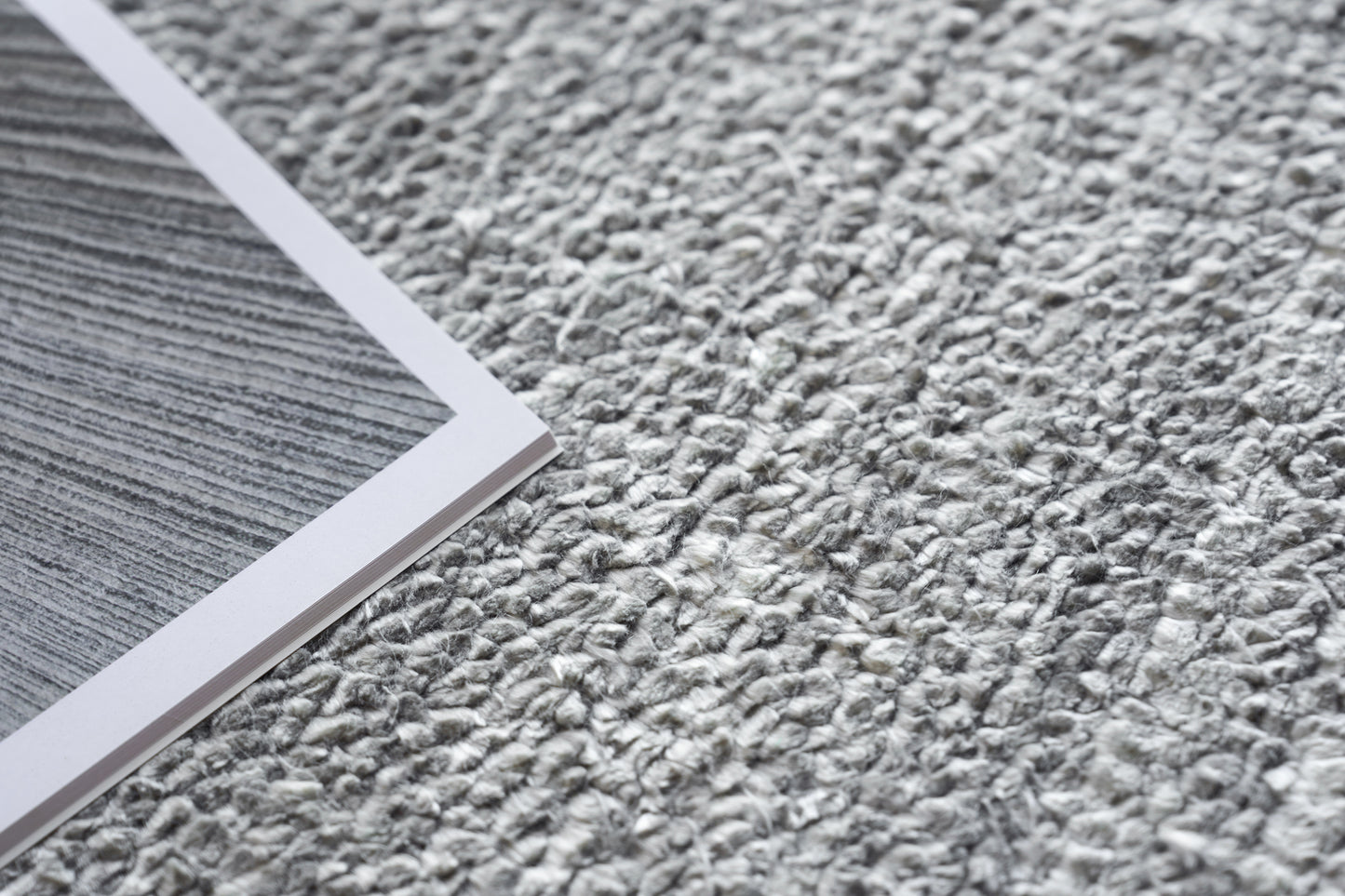 Gray textured rug on the floor with a plush, hand-knotted appearance.