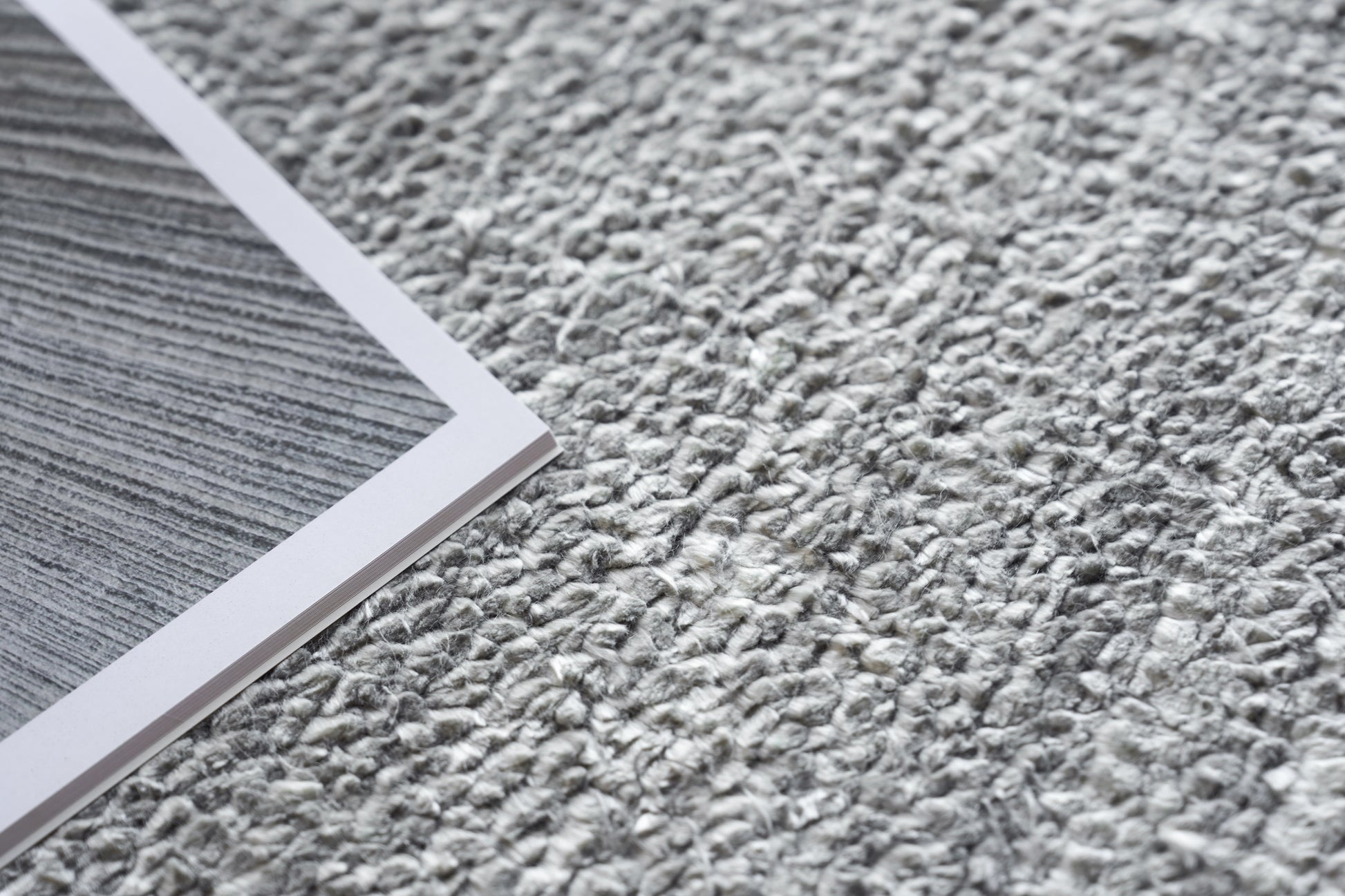 Gray textured rug on the floor with a plush, hand-knotted appearance.