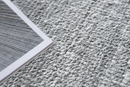 Gray textured rug on the floor with a plush, hand-knotted appearance.