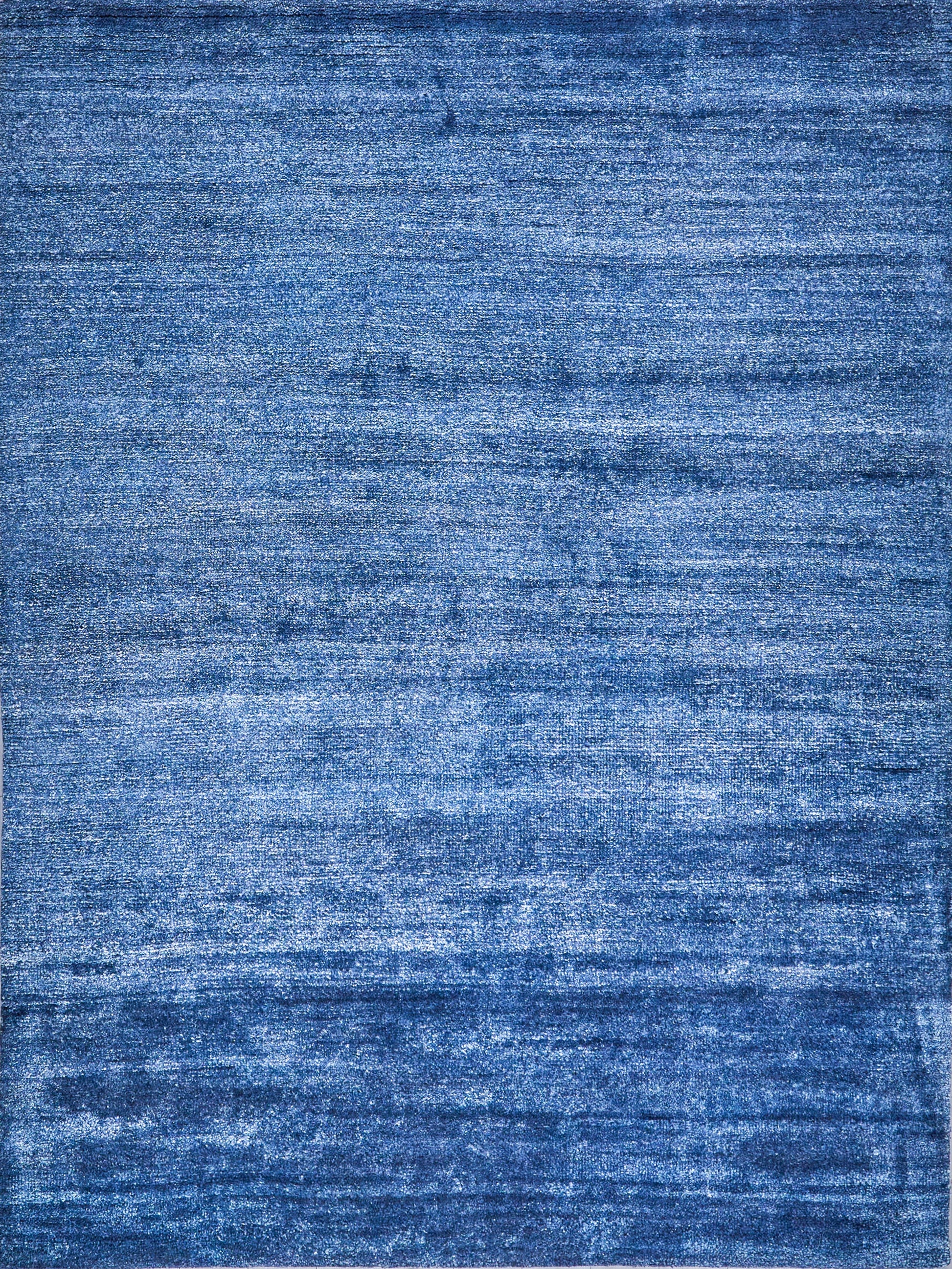 Blue distressed-texture rug with soft pile and varied indigo tones.