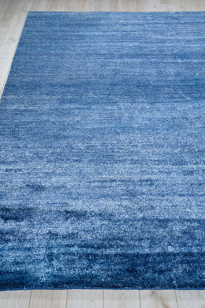 Rectangular blue rug with a subtle gradient and soft plush pile on a light wood floor.