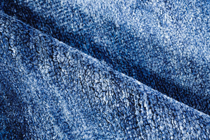 Close-up of blue plush hand-knotted rug fibers with a textured weave.