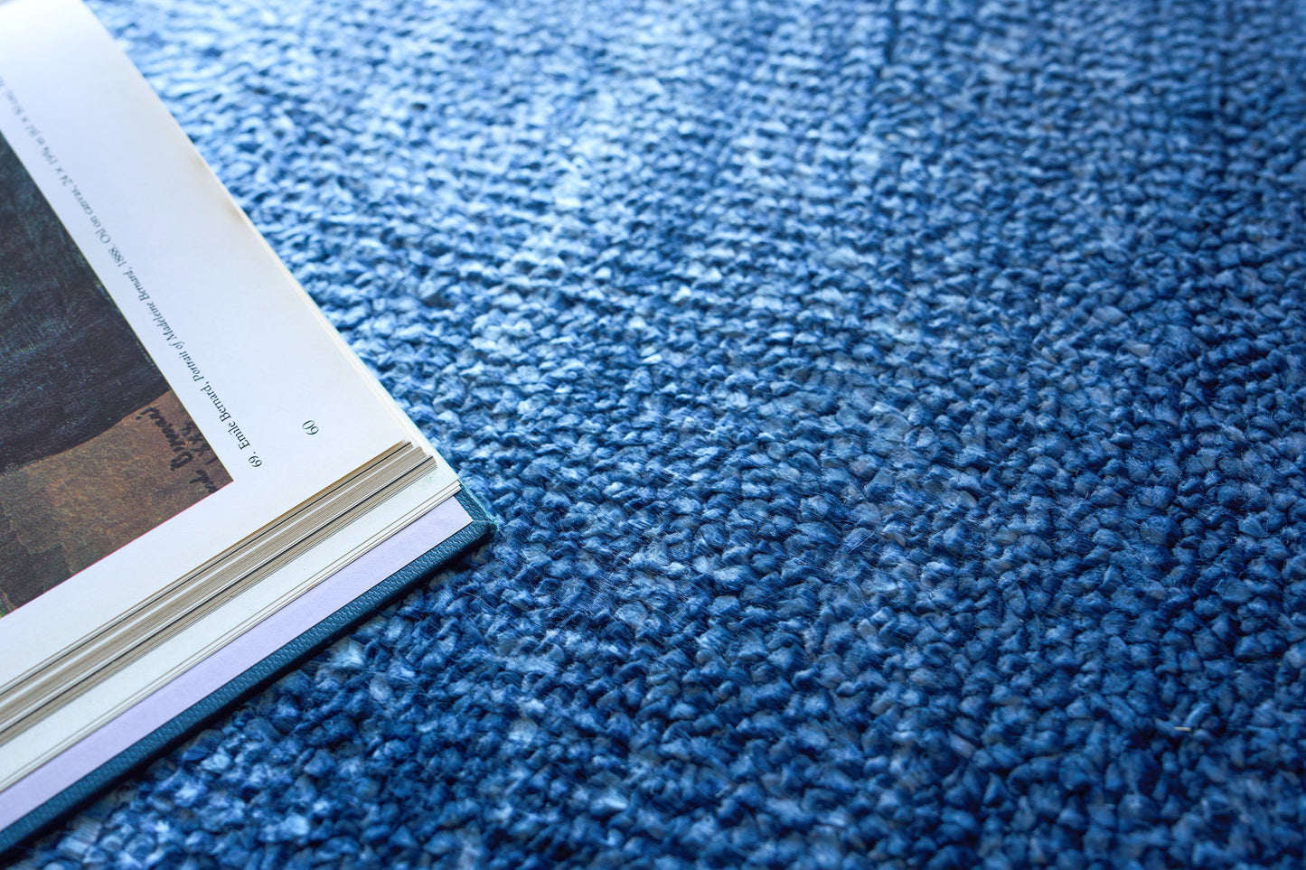 Open magazine on a blue textured rug, pages showing photos.